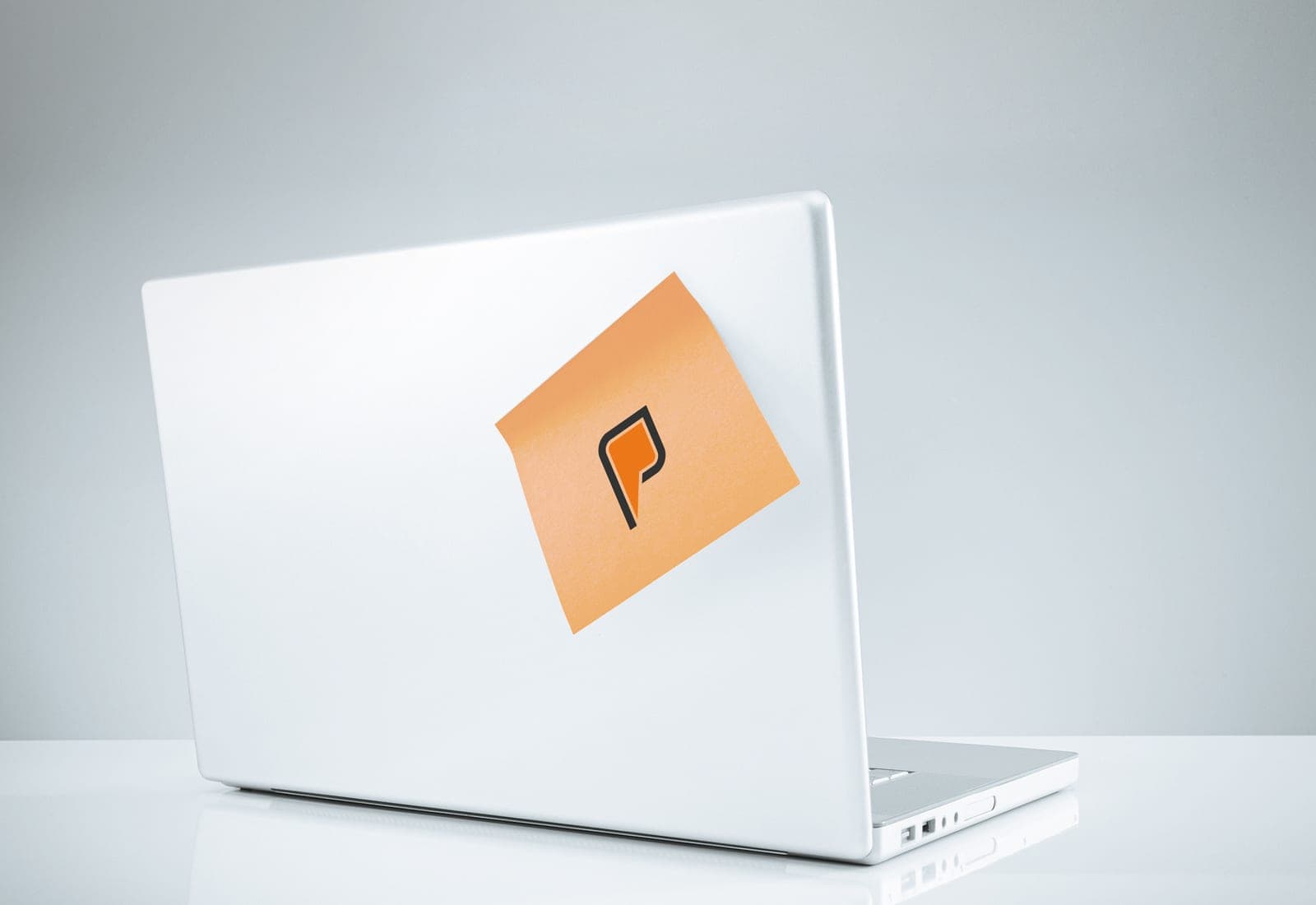 Derselbe Laptop, zugeklappt, mit einer einzigen Haftnotiz mit dem Pales-Zeichen